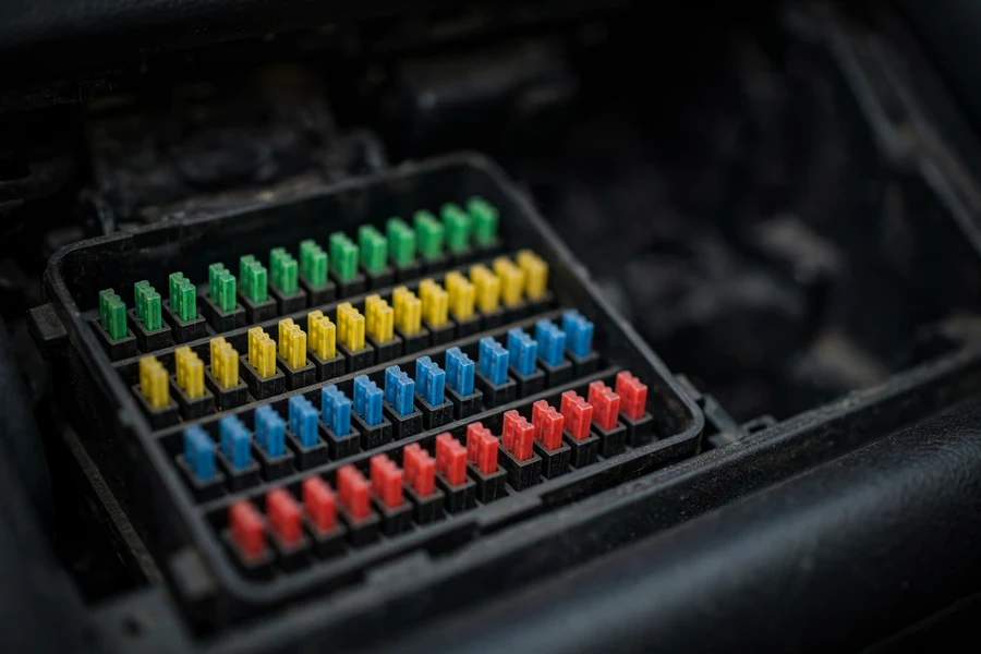 Close-up of colored mini blade fuses inside a BMW 3 Series glovebox fuse box