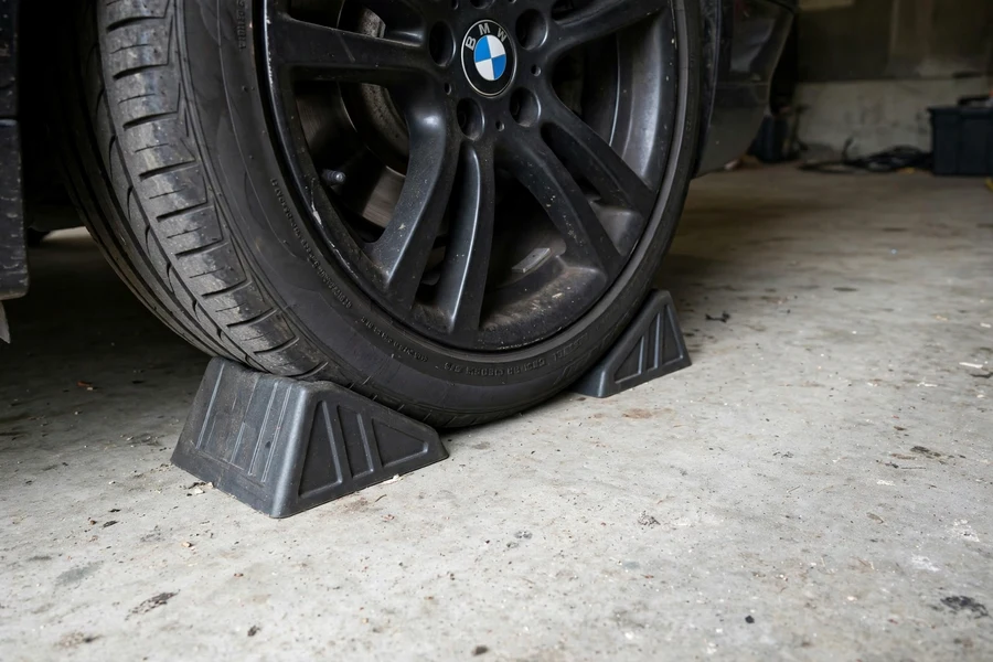 Wheel chocks wedged against a BMW tire on a level garage floor