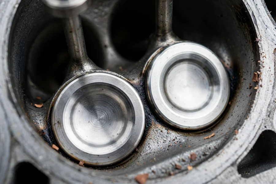 Clean shiny intake valves in a cylinder head port after walnut blasting, with bare metal visible