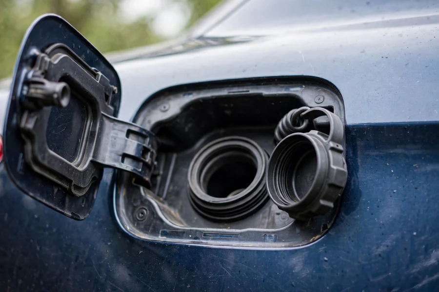 Open BMW fuel filler door with the fuel cap resting beside it
