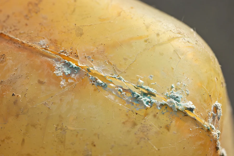 Close-up of an aged yellowed coolant expansion tank with a hairline crack and dried coolant residue