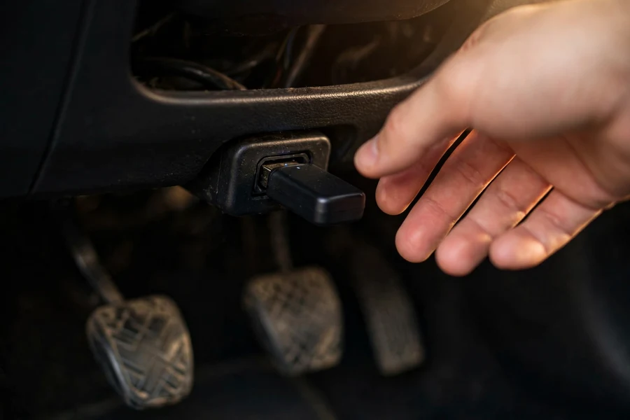 Bluetooth OBD2 adapter plugged into a BMW's OBD2 port under the dashboard