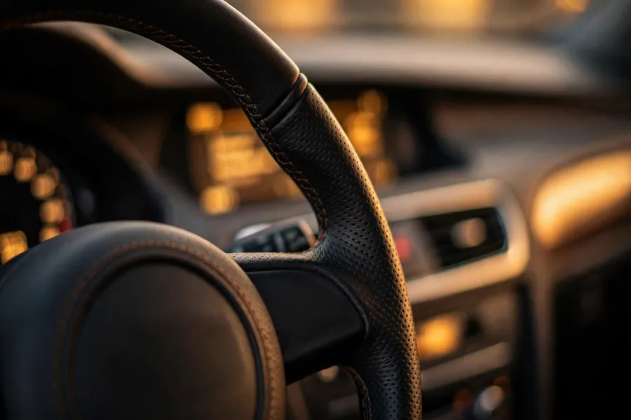 Close-up of a BMW steering wheel and driver-focused cockpit with analog-style gauges