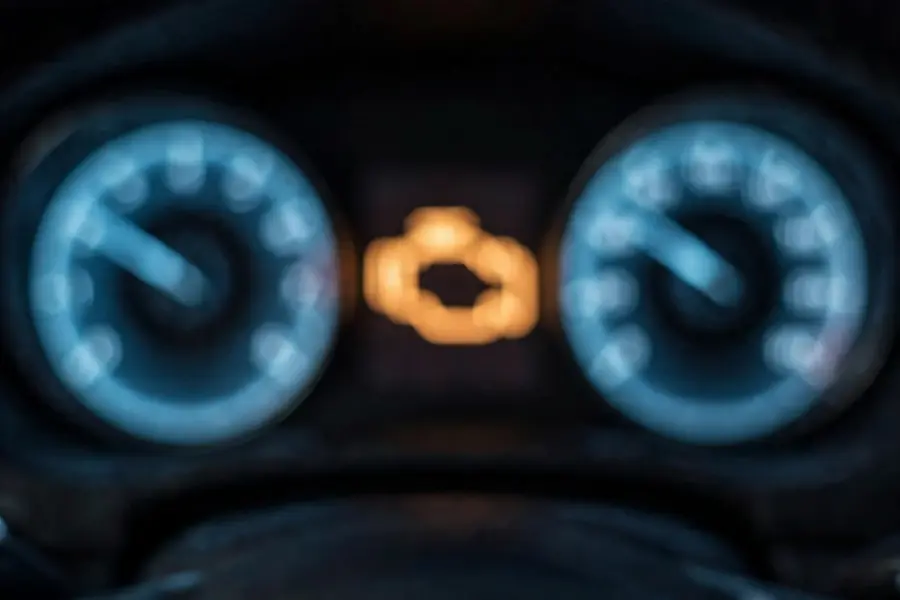 Close view of a 3 Series instrument cluster at night with the amber engine warning light illuminated