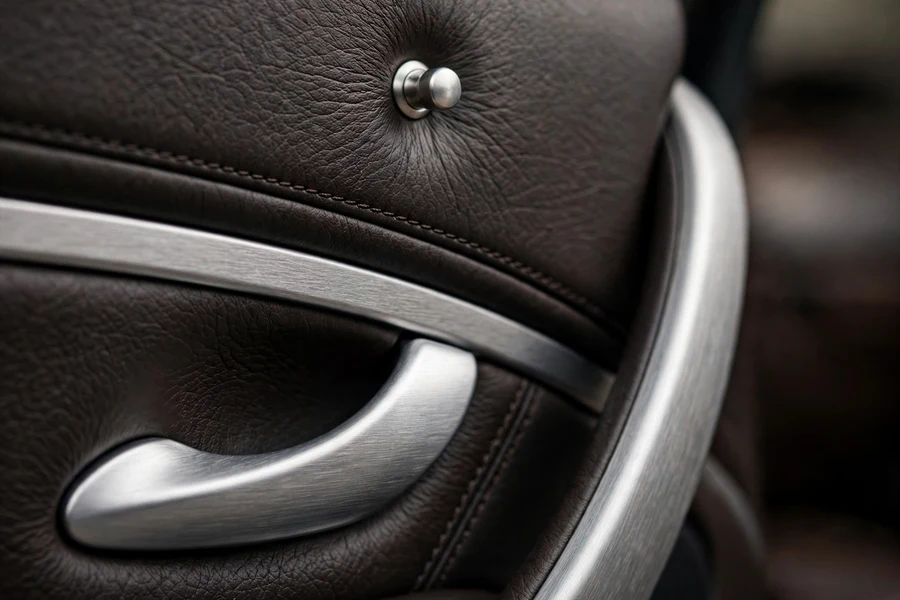 Close-up of a car interior door handle and lock pin on a dark leather door panel