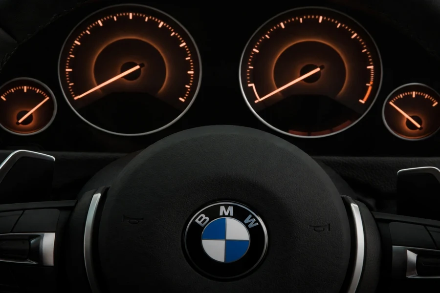 BMW instrument cluster showing an oil-related driver information message during a warm-up check