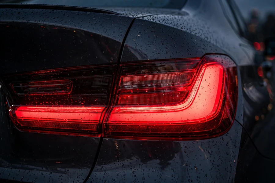 Close-up of a BMW 3 Series taillight lens glowing red at dusk