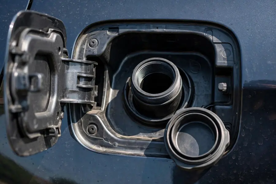 Open BMW fuel filler door showing the filler neck and removed fuel cap with its sealing gasket