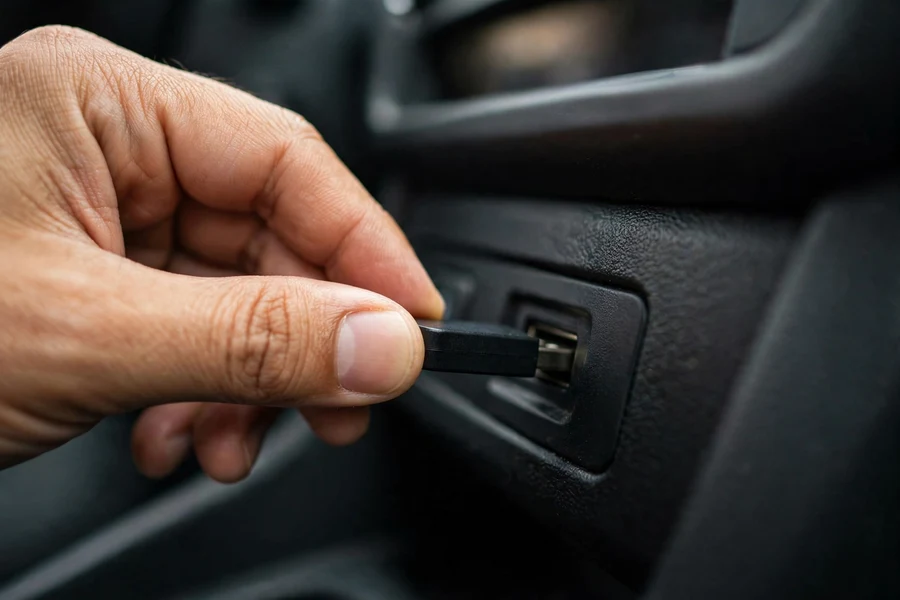 Hand inserting a USB flash drive into a car's center console port