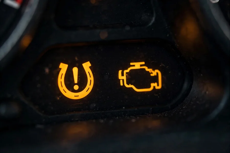 Amber tire-pressure and check-engine warning symbols glowing on a dark dashboard